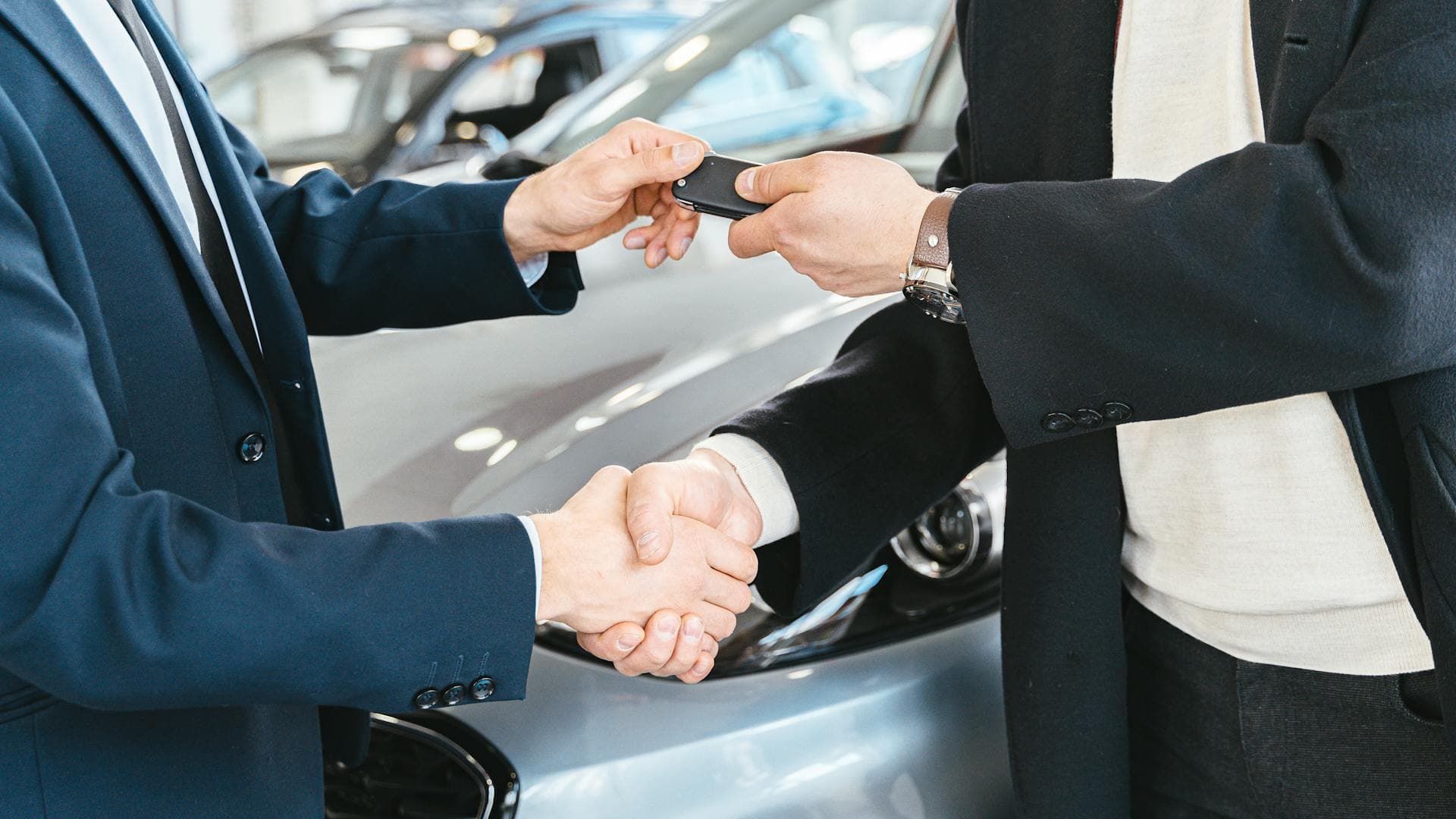 Handshake and car keys being exchanged at dealership